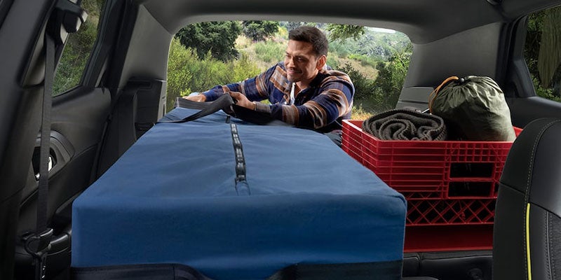 View from inside an SUV cargo area showing camping and outdoor gear loaded in the rear storage space