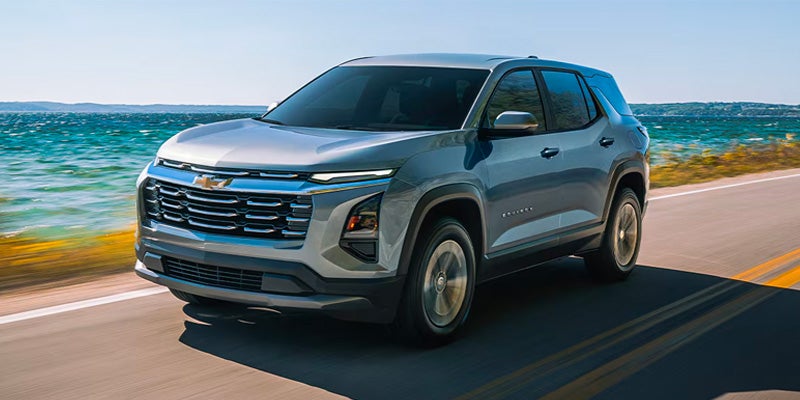 Gray compact SUV traveling along a coastal road with ocean views and clear skies in the background