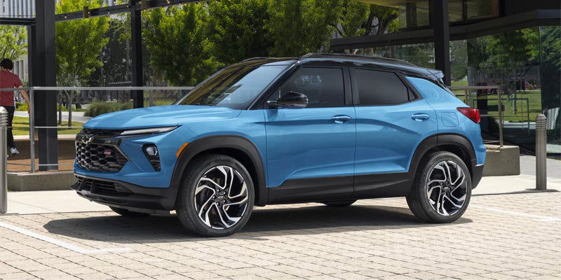Blue compact SUV parked on a paved plaza outside a modern glass-fronted building