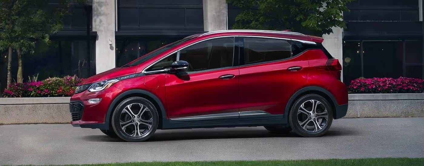 A red 2021 Chevy Bolt EV is shown from the side parked outside of a city building after leaving a Pennsylvania electric car dealer.