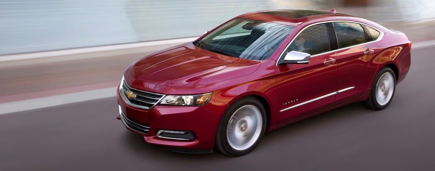 A red 2018 Chevy Impala LTZ is shown driving past a blurred background.