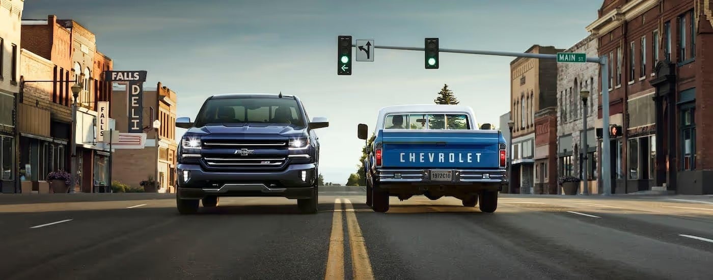 A dark blue 2018 Chevy Silverado Z71 Centennial Edition is driving past a light blue 1972 C10 at a set of traffic lights.