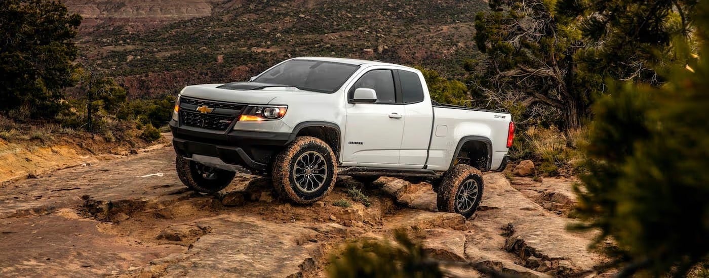 A white 2020 Chevy Colorado, which is a popular model among Chevy trucks, is rock crawling up a hill.