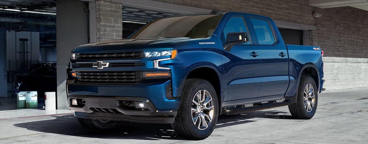 A blue 2020 Chevy Silverado RST is parked in front a garage.