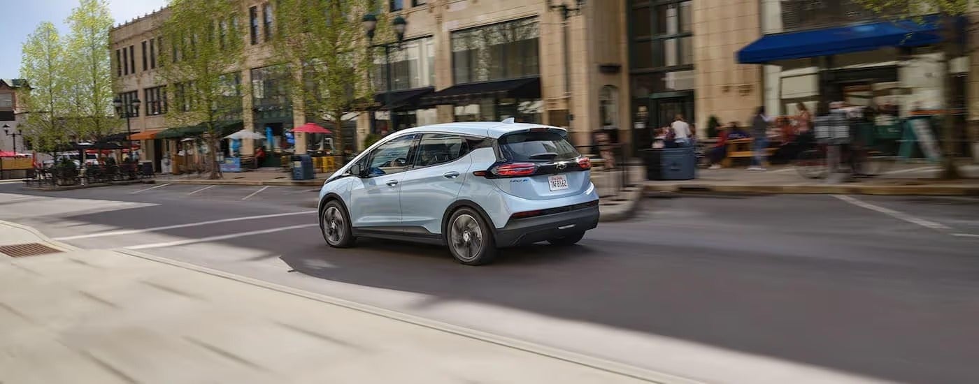 A light blue 2022 Chevy Bolt EV is shown driving on a city street.