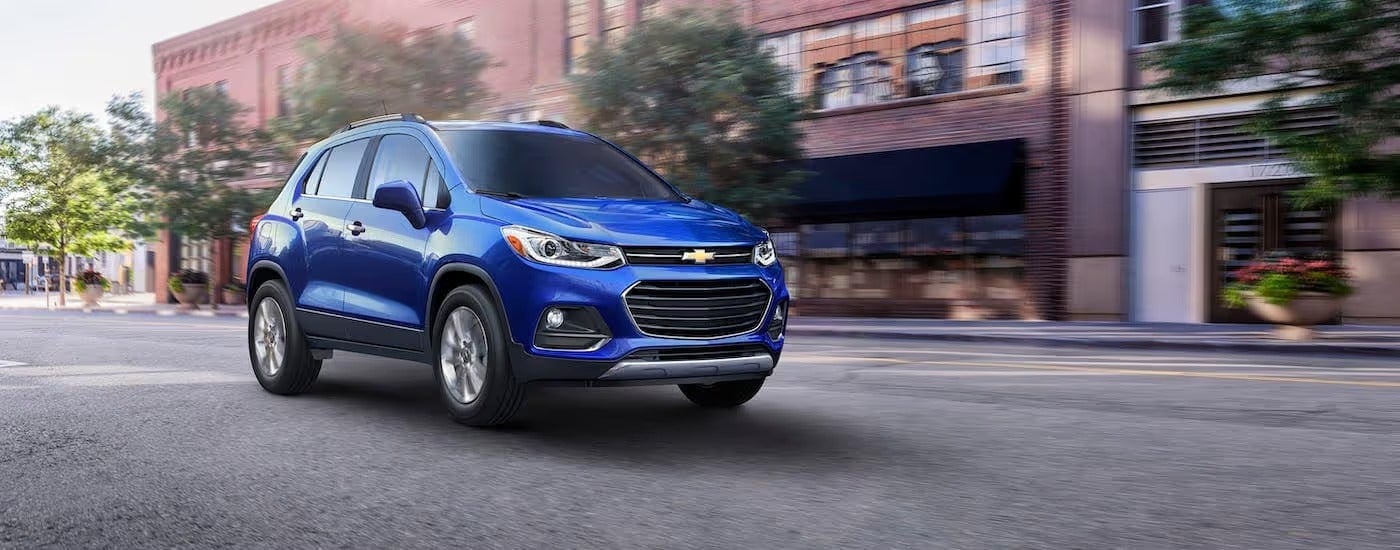 A blue 2018 Chevy Trax is driving on a city street after leaving a used Chevy dealer near Nazareth, PA.